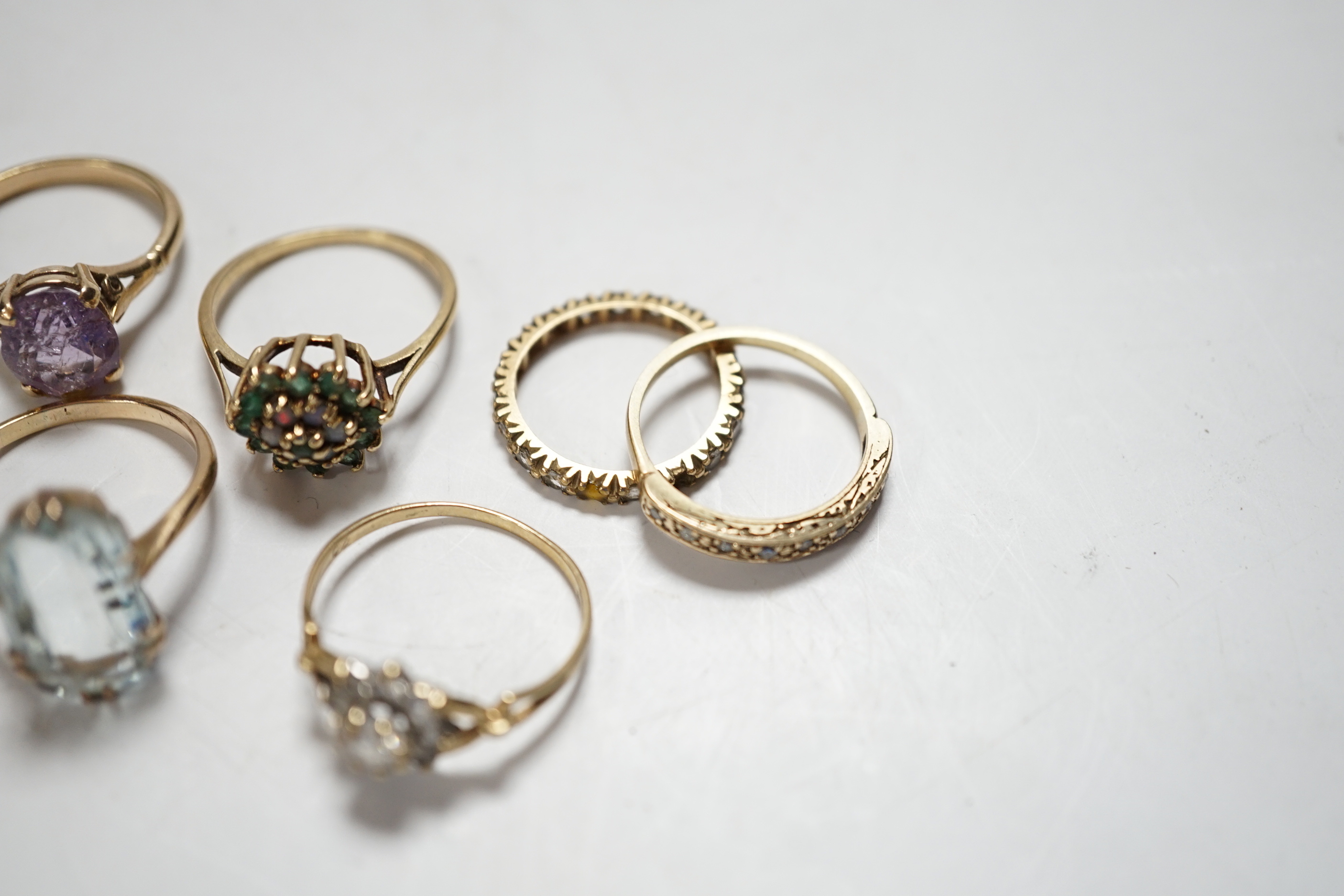 Four assorted modern 9ct and gem set rings including cubic zirconia, two other yellow metal and gem set rings including aquamarine and a yellow metal and multi gem set stick pin, gross weight 15.8 grams.